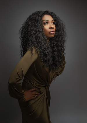 Dramatic fashion portrait in olive colored top with dynamic poses against dark studio background.