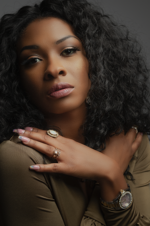 Artistic portrait featuring olive top and statement jewelry with dramatic side-lit composition.