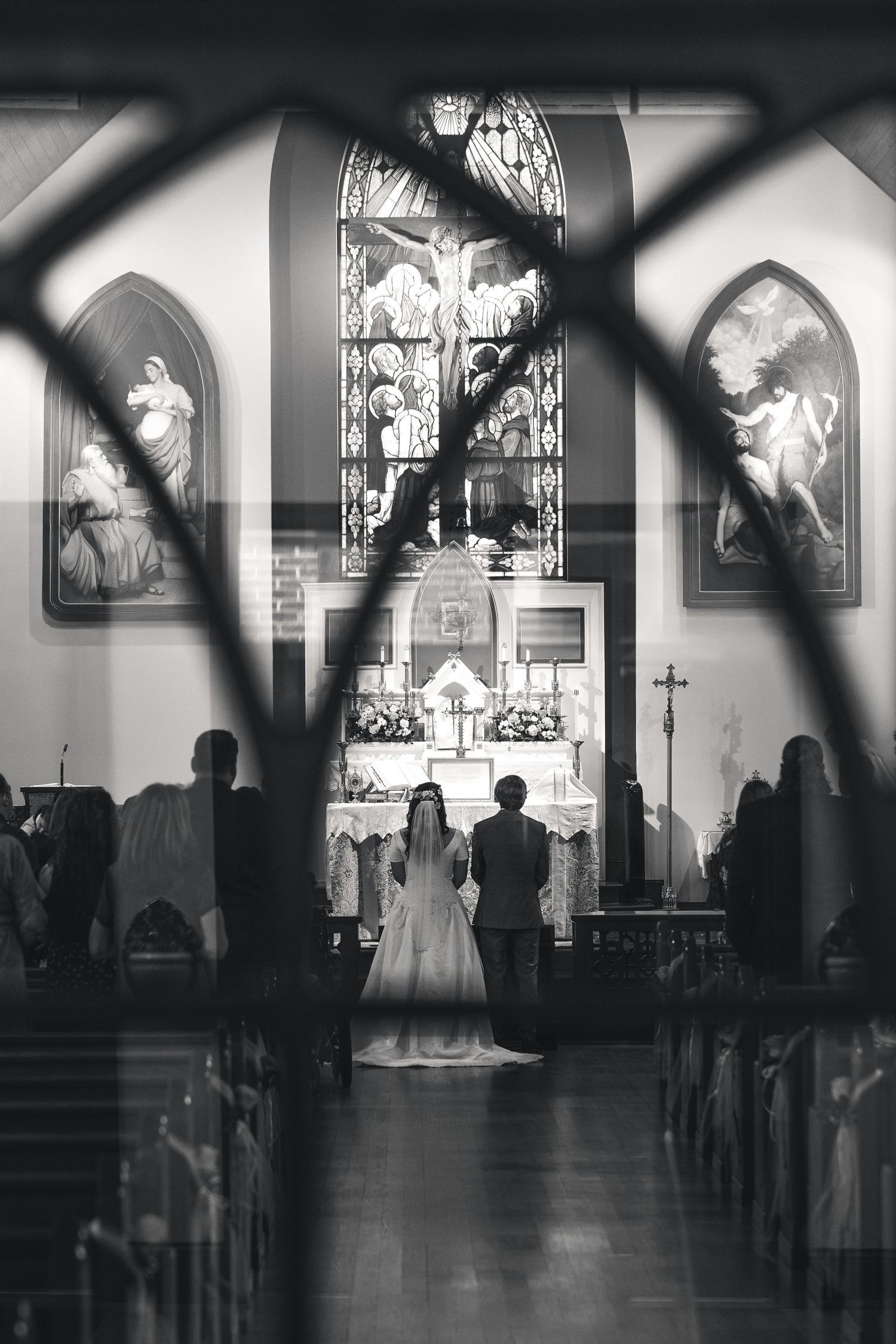 Black and white panoramic view of a church interior showing stained glass windows and arched architecture in silhouette.