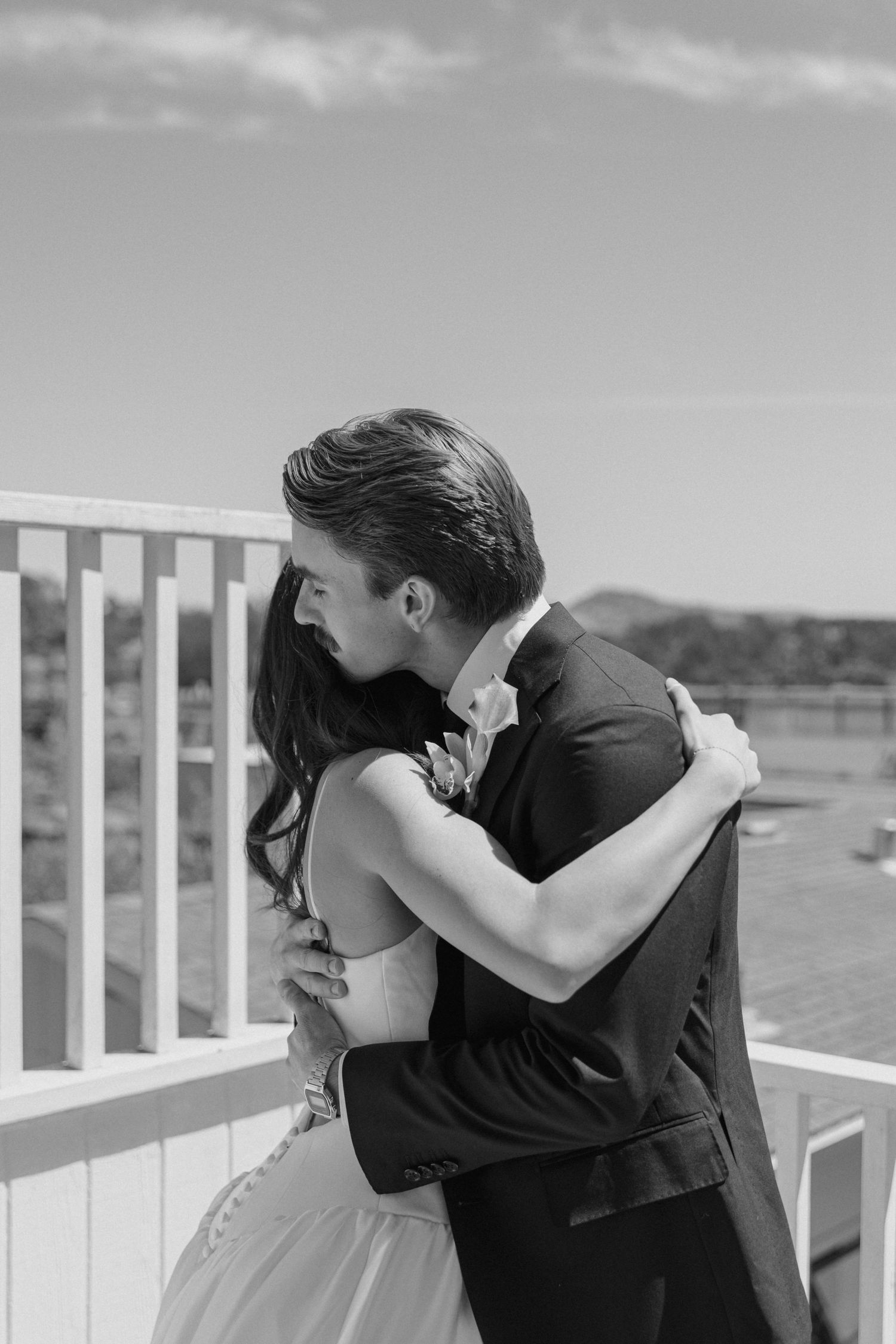 A romantic black and white photo series showing a couple embracing on a seaside deck.