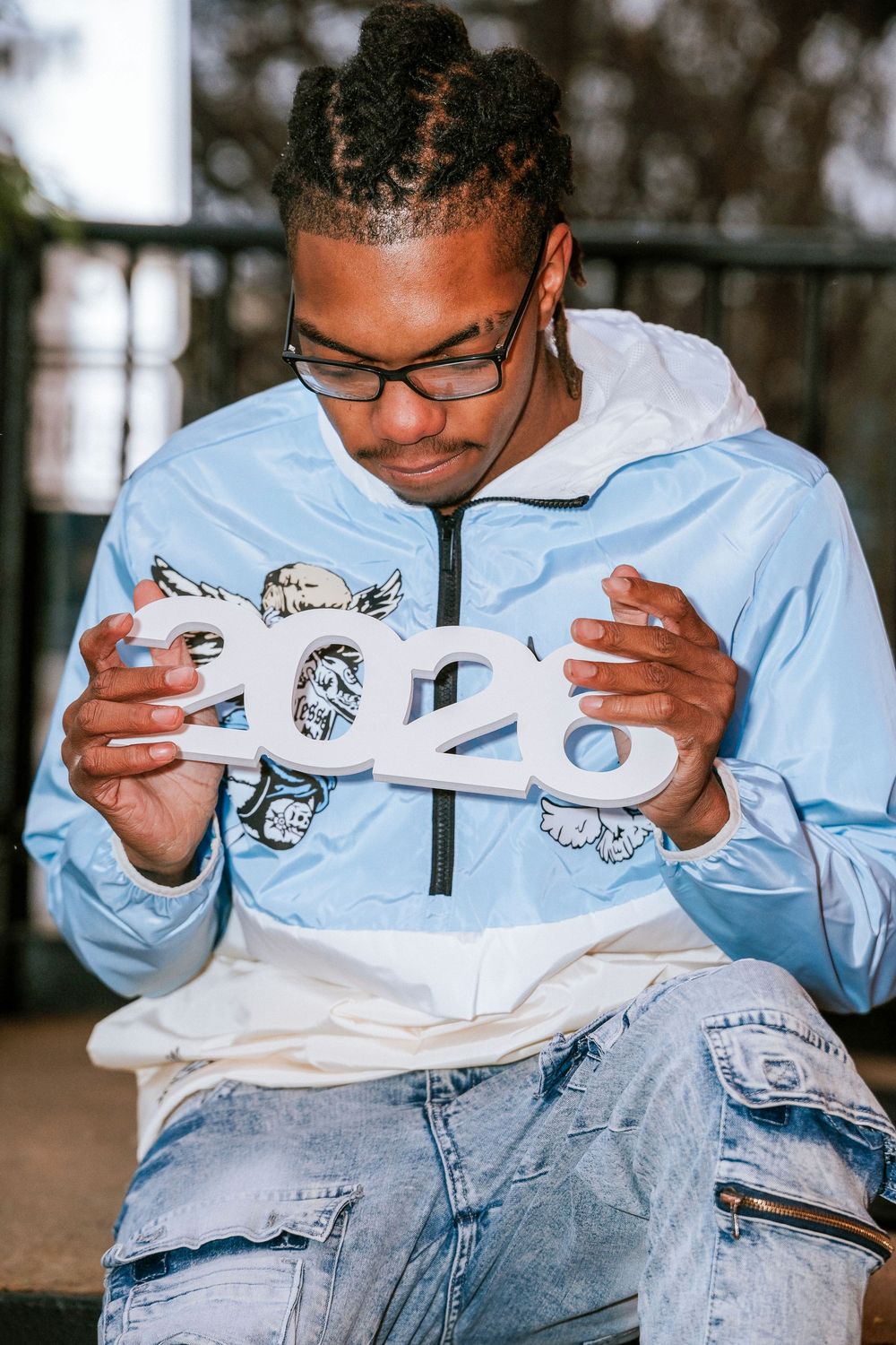 Person wearing light blue hoodie examining white sneakers.