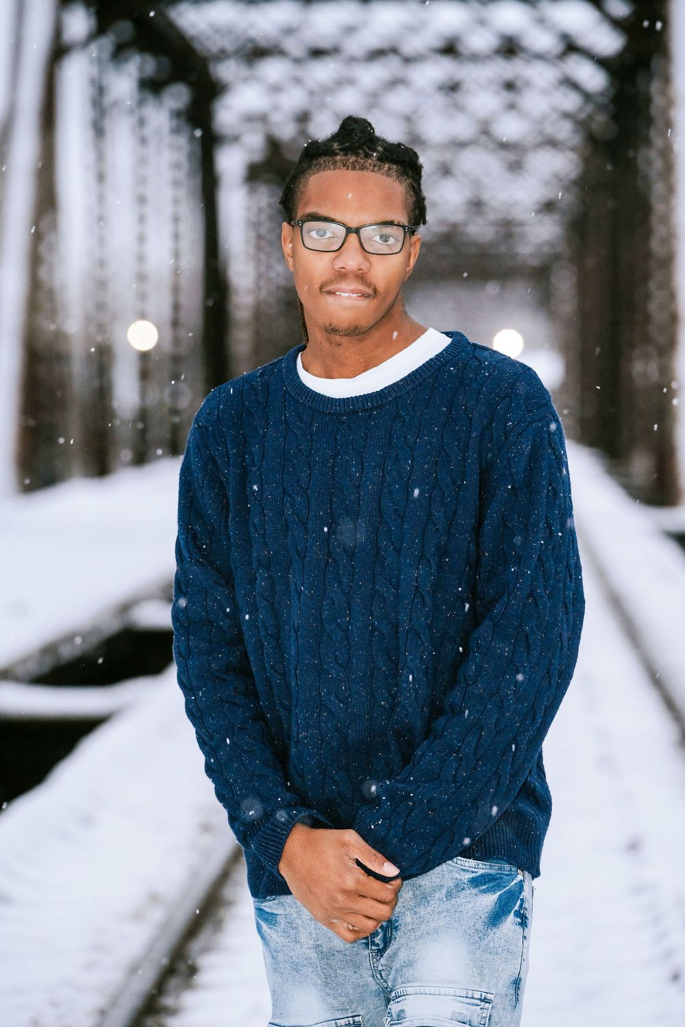 Person in navy sweater sitting in snowy winter setting.
