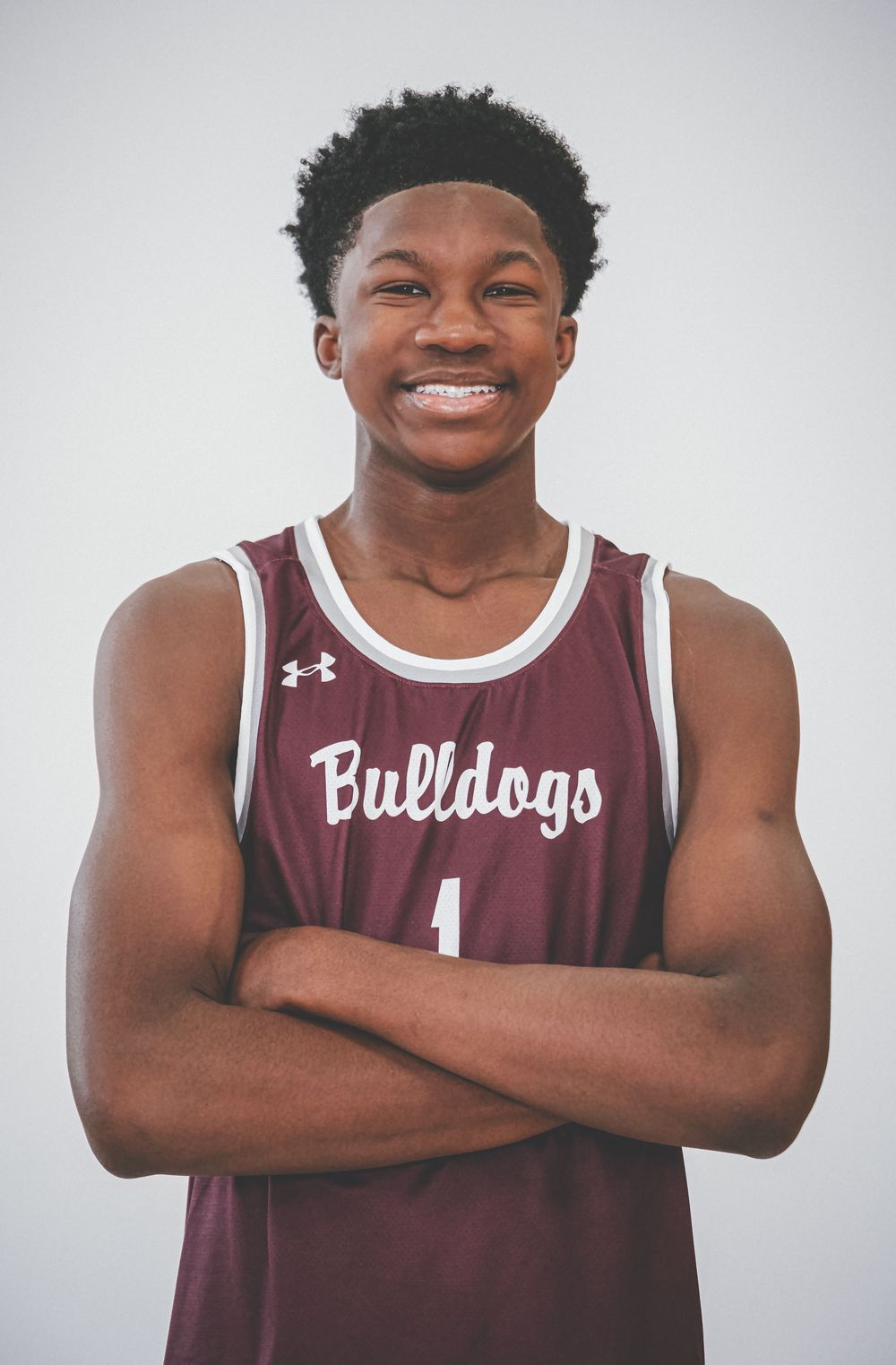 Basketball player in maroon Bulldogs jersey poses with crossed arms.
