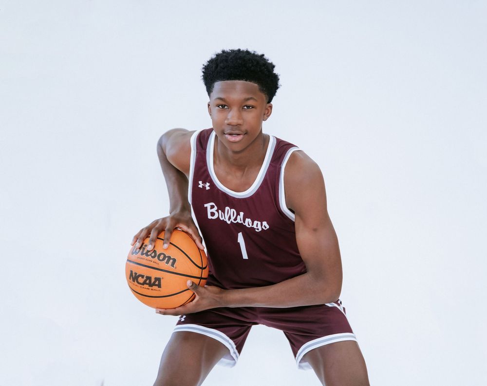 Basketball player in maroon jersey holding a ball in athletic pose.