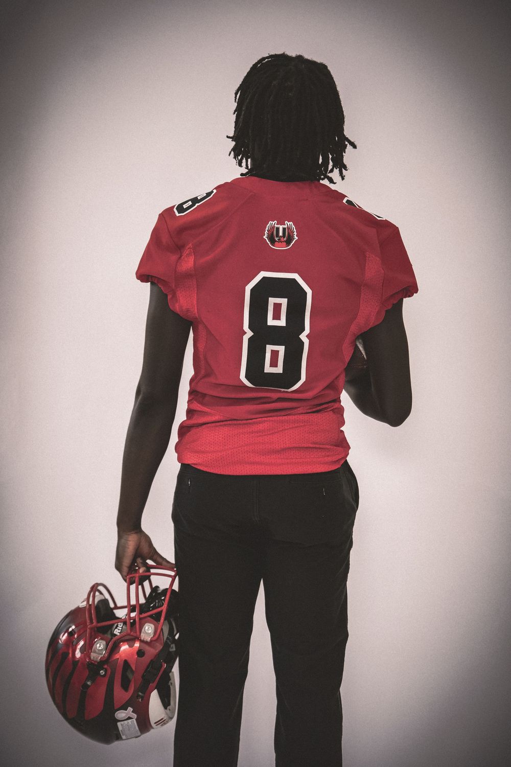 Athletic figure in red jersey number 8 shown from behind with sports bag.