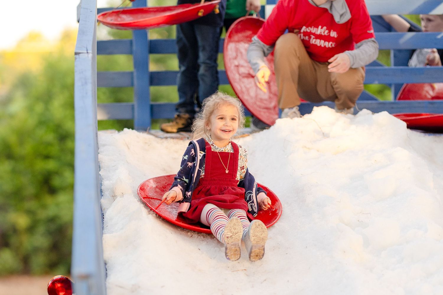 Red and white snow cone machine with ice shavings visible in a summer outdoor setting.