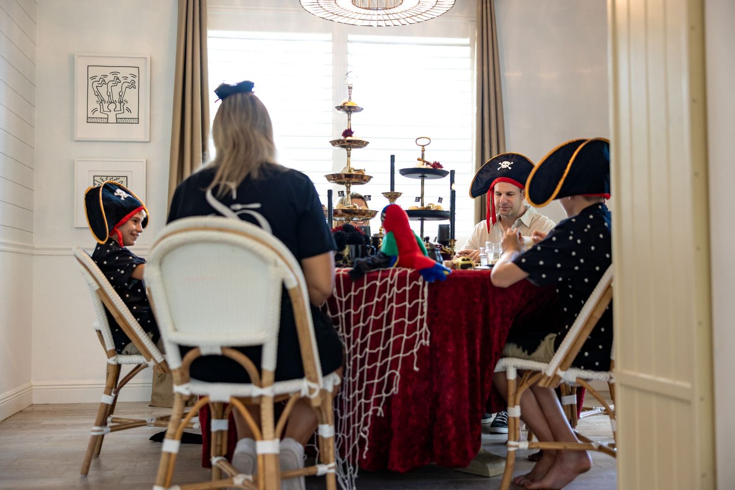A group of people sit at a long table during an afternoon tea service with tiered serving platters and teacups.