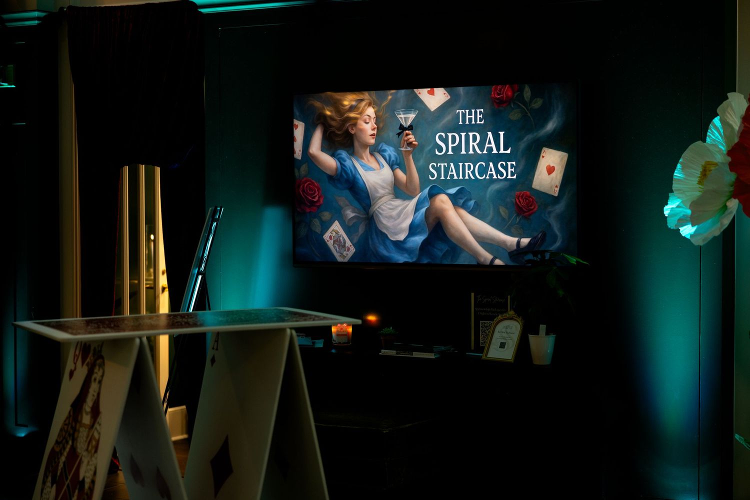 A podcast recording setup with a display screen showing 'The Spiral Syndicate' logo in a dimly lit studio space.