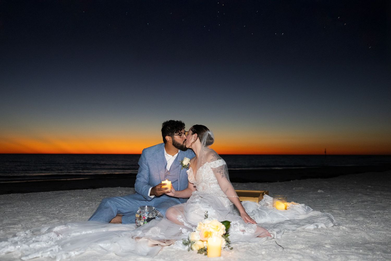 A couple shares a romantic moment on a snowy winter evening at sunset with warm glowing light in the background.