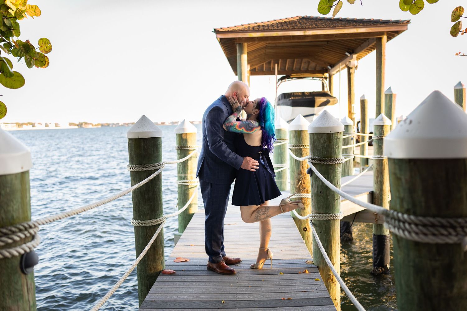 A romantic engagement photo session on a wooden dock overlooking the water at sunset.