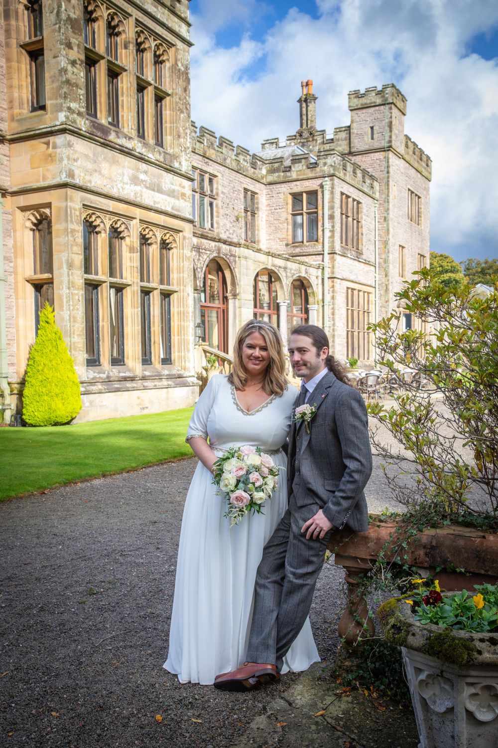 Bride and groom pose together in gardens of stunning historic castle wedding venue.
