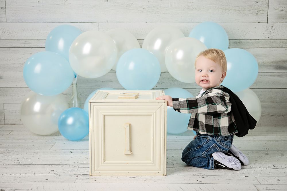 White wooden block with number one against blue and white balloon background.