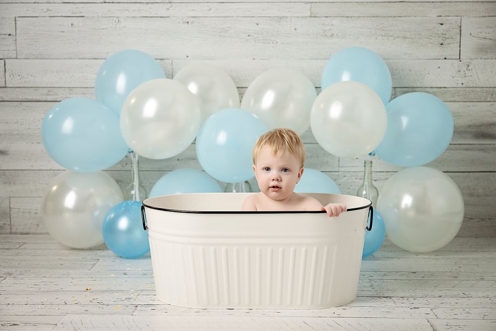 First birthday bath setup with white tub against blue and white balloons.