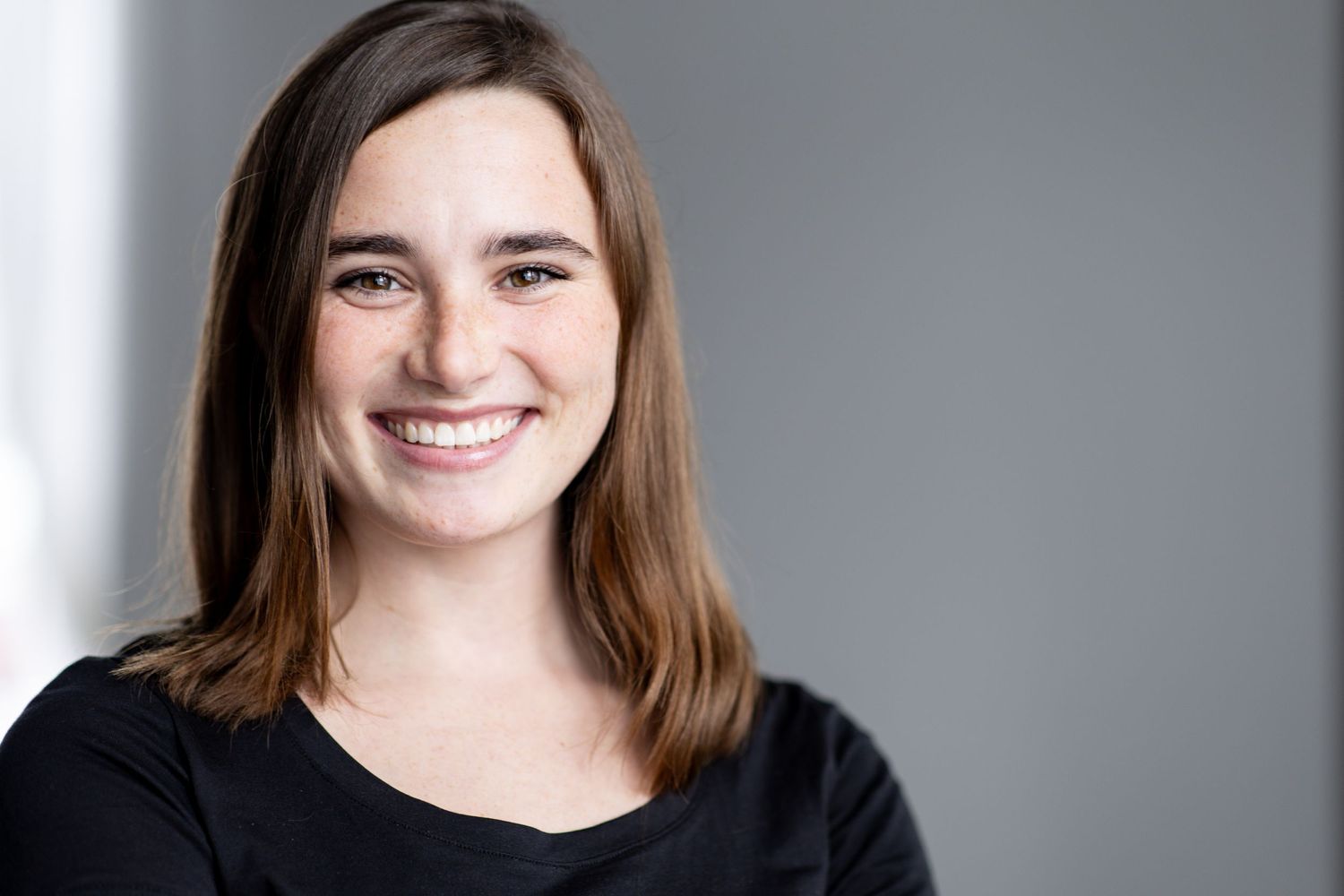 Professional headshot portrait with soft lighting against a neutral gray background.