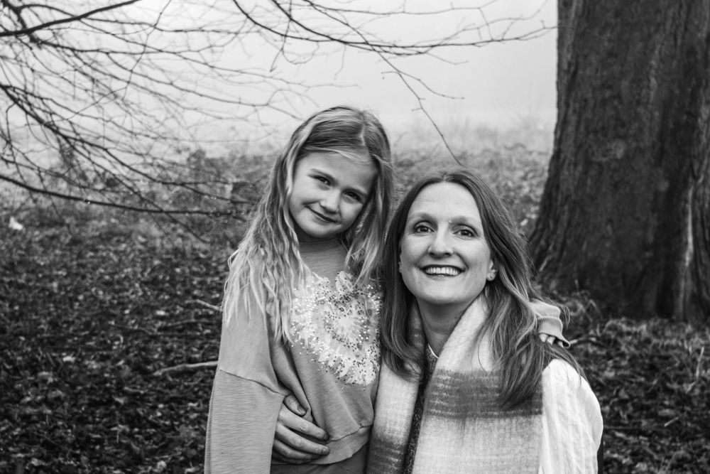 A black and white portrait of two people smiling together outdoors.