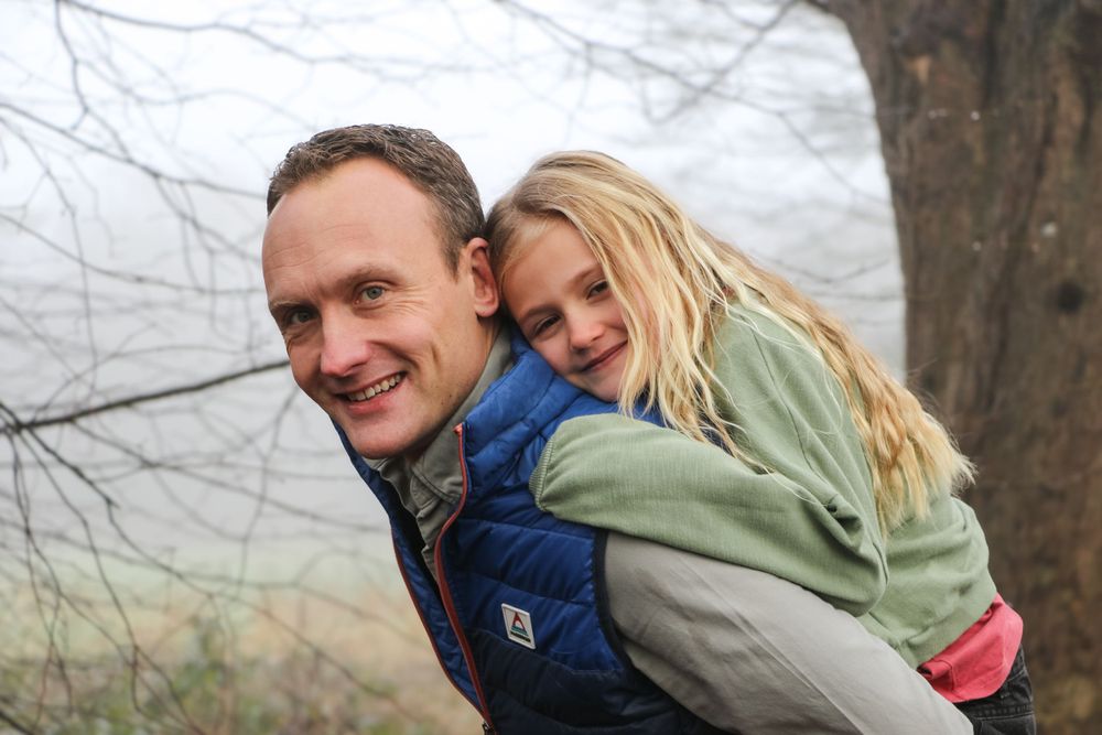 Outdoor piggyback ride against misty winter forest backdrop.