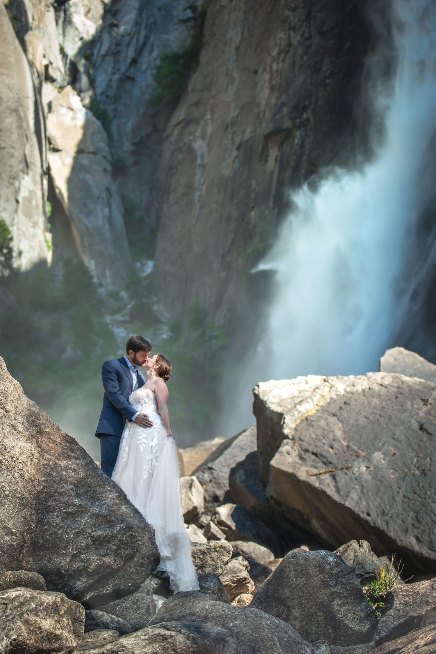An elegant newly wedded couple kissing under Yosemite Falls