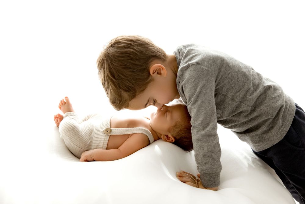 Newborn baby brother with big brother touching noses