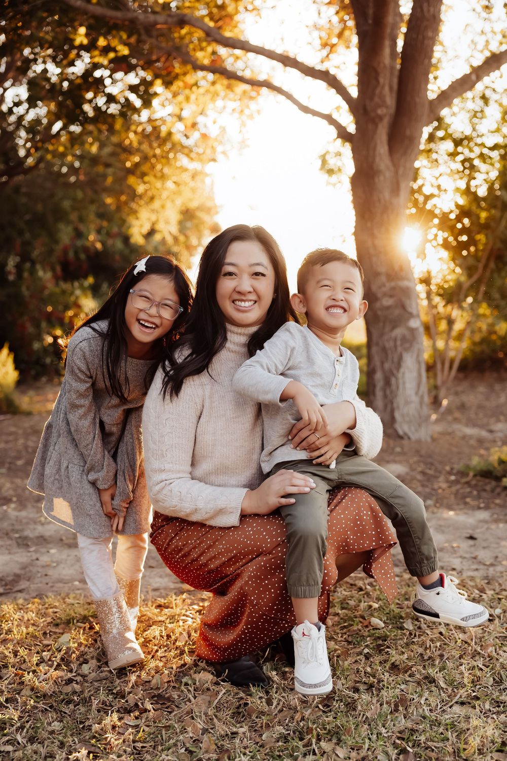 Joyful outdoor family portrait during golden hour beneath autumn tree.