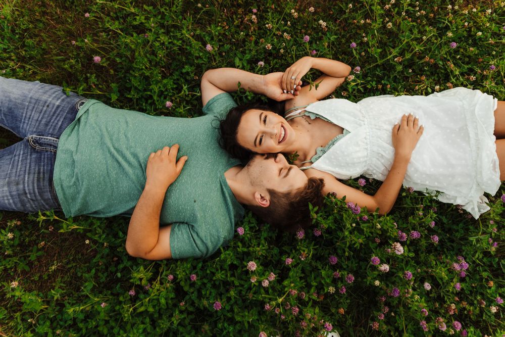 Couple lying on grass together sharing laughs.