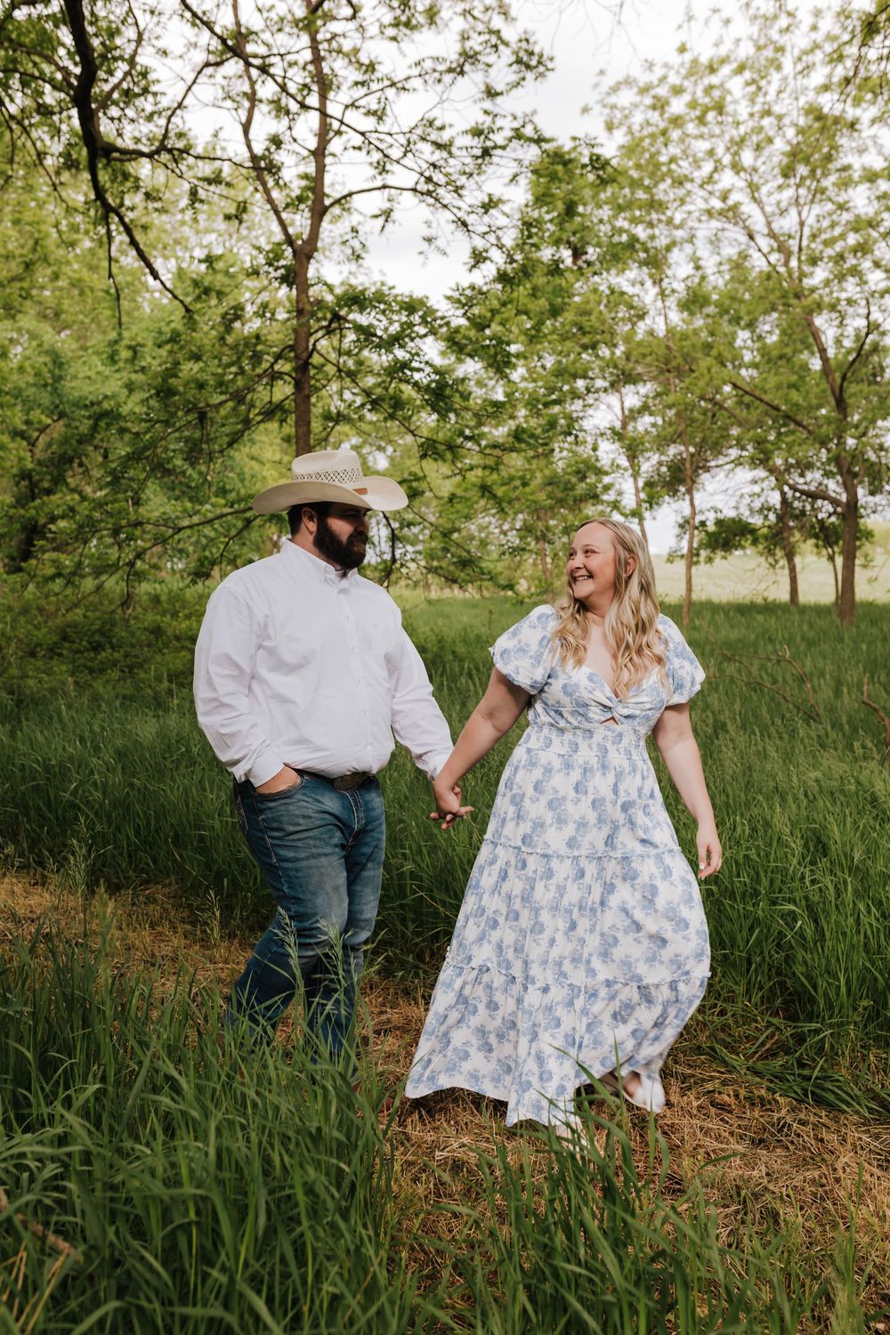 A couple in a field with tall grass shares playful moments in a series of romantic outdoor photos.