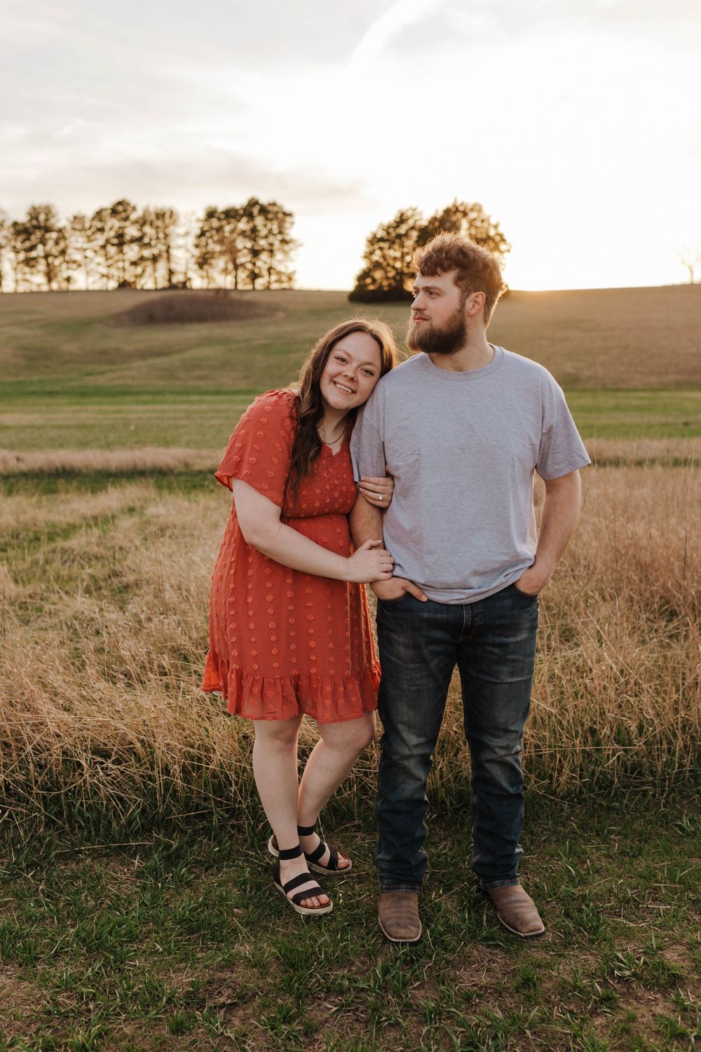 A couple shares a romantic moment together in a golden field at sunset.