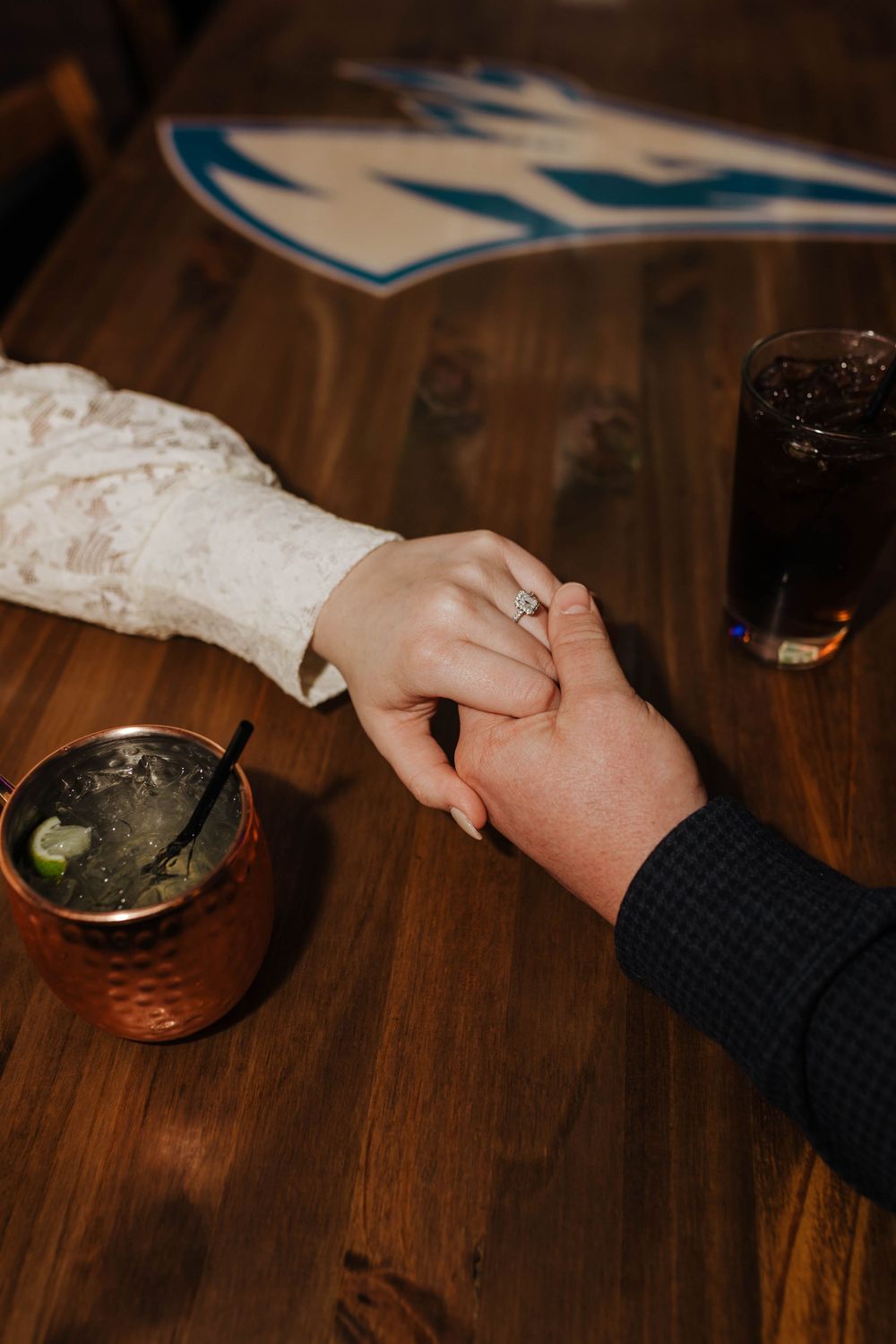 Close-up of hands holding on wooden table with copper mug and drinks.
