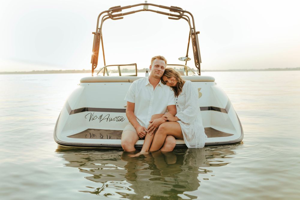 Couple relaxing together on white speedboat during sunset on calm waters.