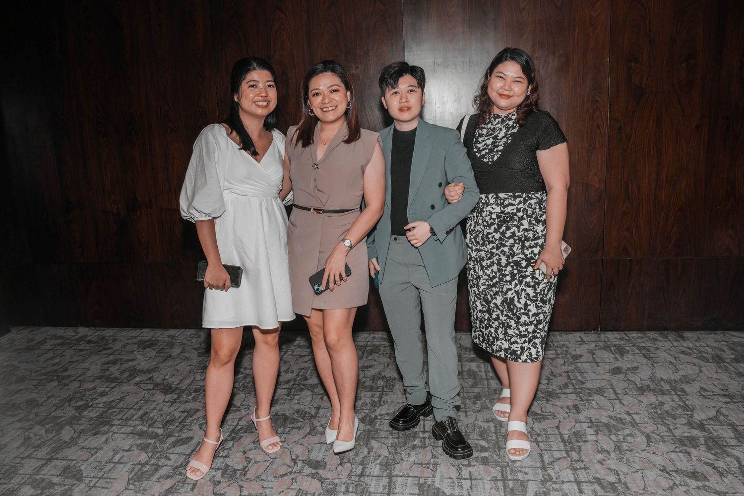 Group photo against wood paneled wall in a formal setting.