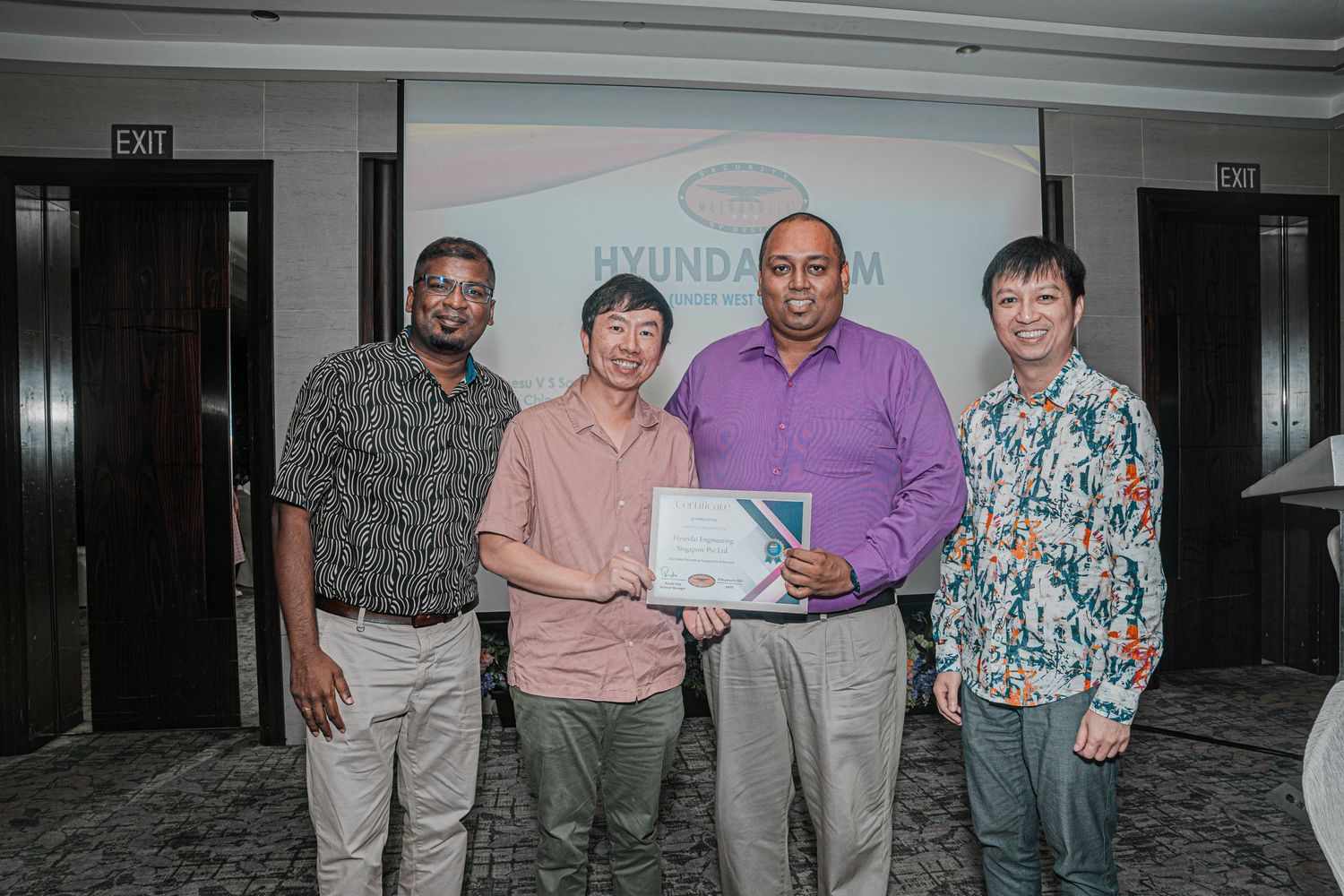 A group stands together holding an award or certificate in a conference room setting.