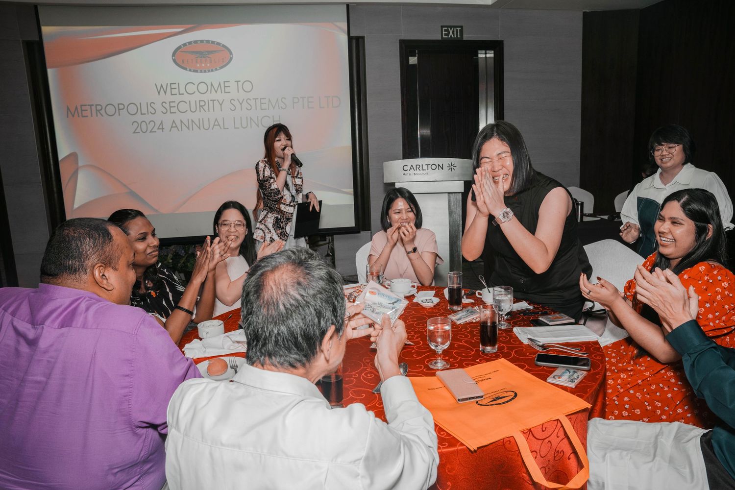 Corporate event with attendees engaged in discussion around tables with orange tablecloths.