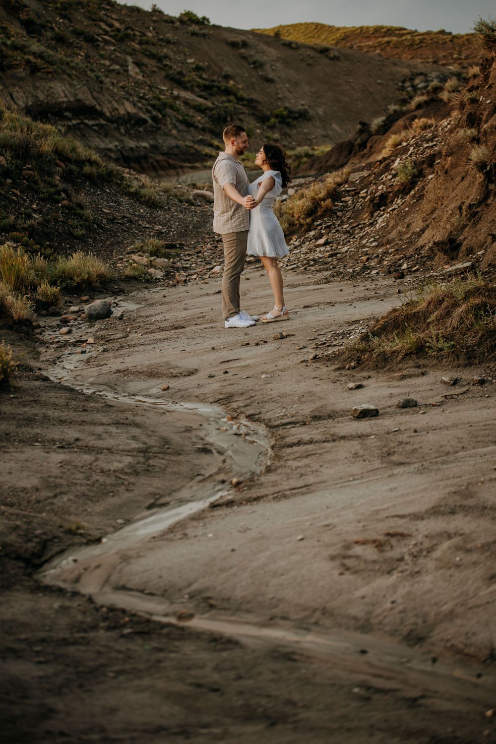 Couple embraces on winding desert path during golden hour.