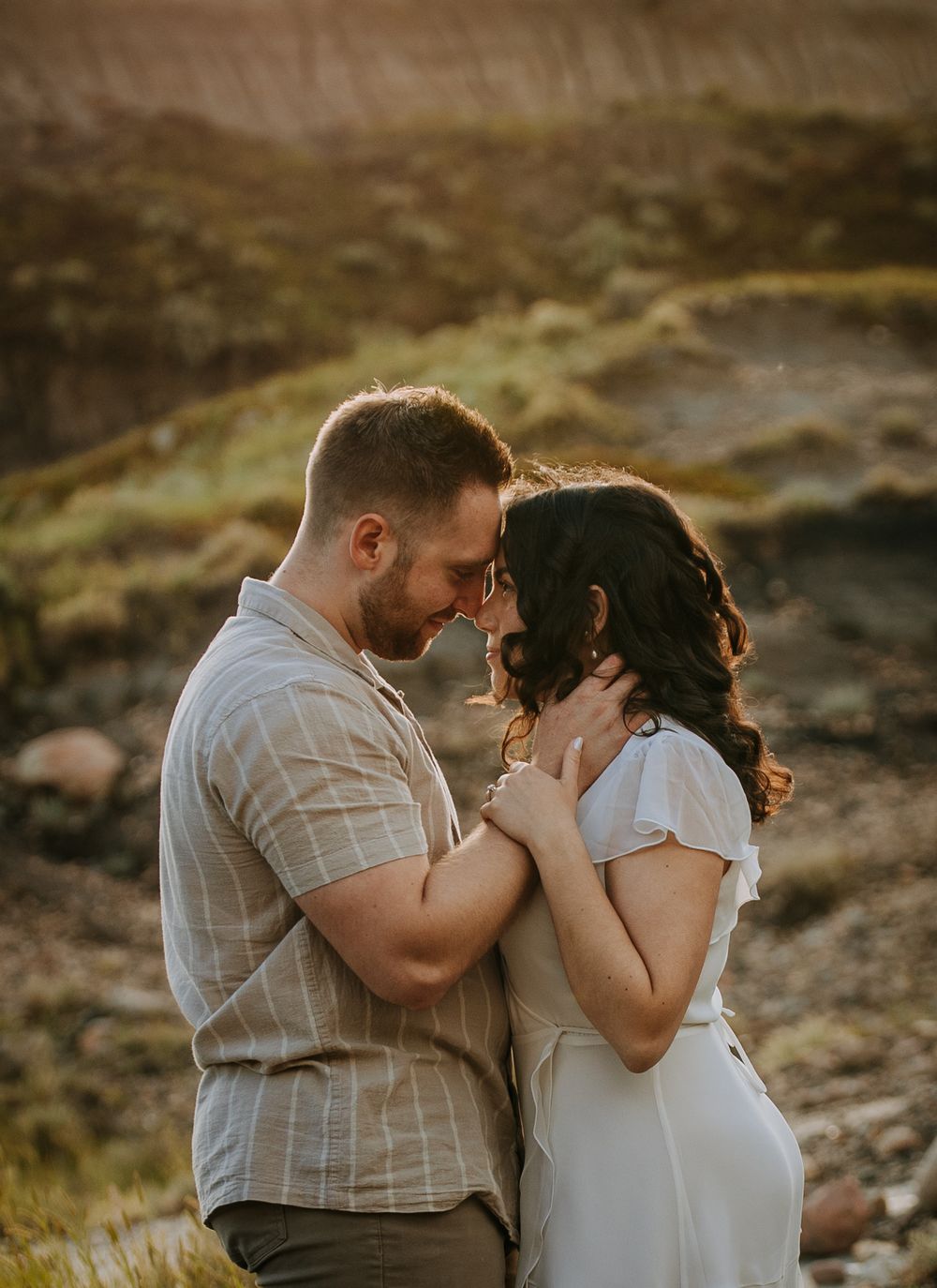 An intimate moment between a couple against a dramatic mountain backdrop at sunset.