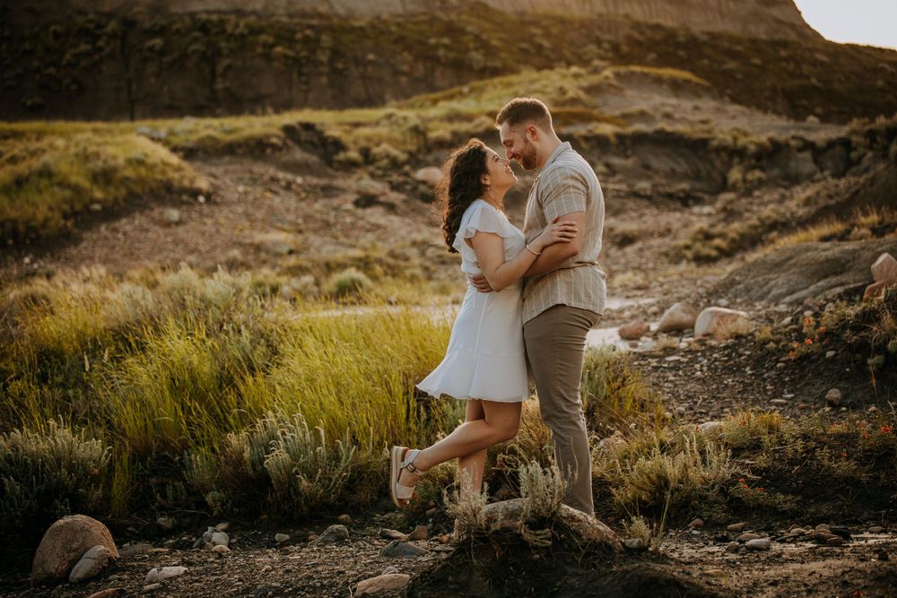 A romantic couple sharing a loving moment in front of a golden mountain landscape.