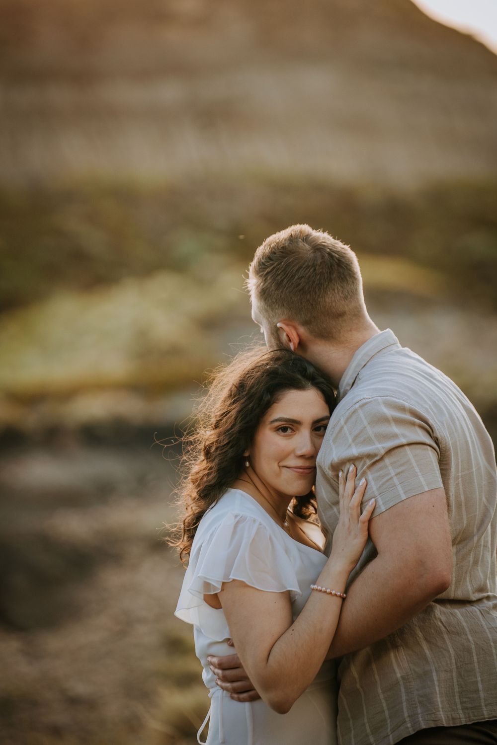 A tender embrace captured in warm sunlight with mountains in the background.