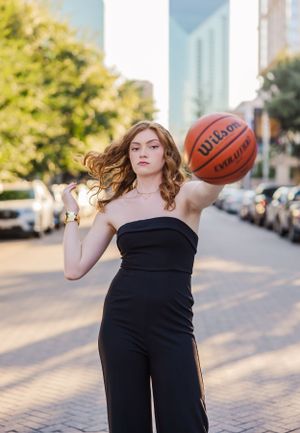 Urban portrait session with someone in black attire posing with a basketball on cobblestone streets.