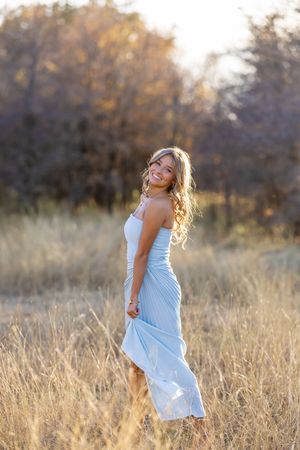 Light blue dress flows gracefully in autumn field during sunset.