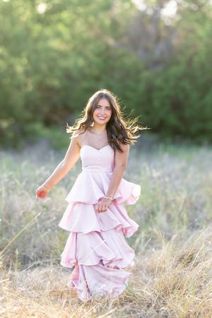 Pink layered dress dances in the breeze among wild grasses at sunset.