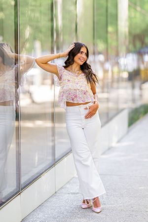 Modern fashion photoshoot featuring white outfit against reflective glass windows.