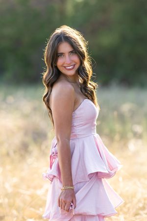 Soft pink dress glows in natural light during outdoor portrait session.