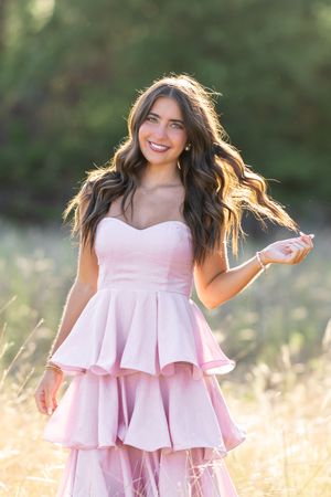 Light pink ruffled dress creates movement in golden sunset field.