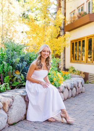 A portrait session on stone steps featuring someone in a flowing white dress against autumn foliage.