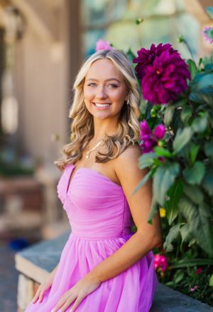 Outdoor portraits near vibrant purple flowers with someone wearing a pink formal dress.