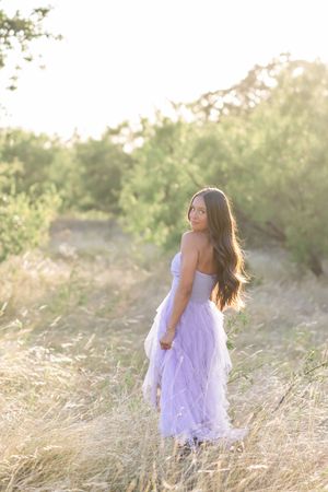 Romantic portraits in a white lace dress among sun-kissed wild grasses.