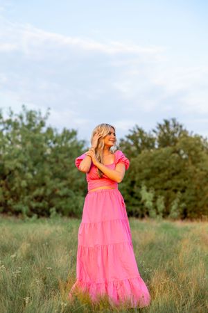 A bright coral pink dress flows in the breeze during an outdoor photoshoot.