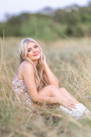 Dreamy portrait session in a sunlit field with soft golden light and tall grass.