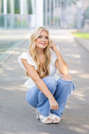 A casual portrait in light denim and white against a soft outdoor background.