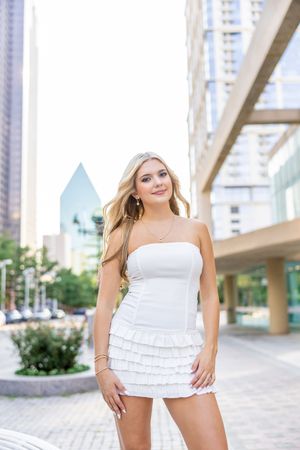 Summer fashion portrait in a white ruffled dress against modern architecture.