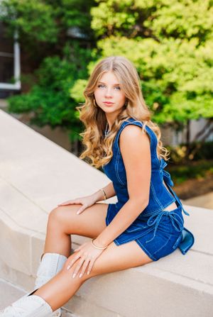 Portrait series in a blue outfit posing on concrete steps with natural lighting.