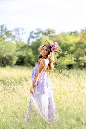 A person in a flowing white dress dances joyfully through a sunlit field of tall golden grass.